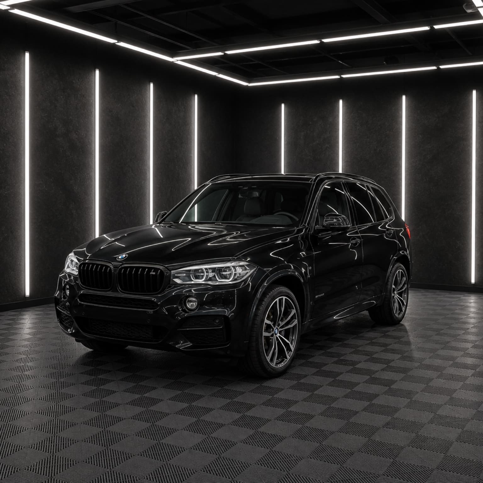 Black BMW X5 inside a dark automotive studio.