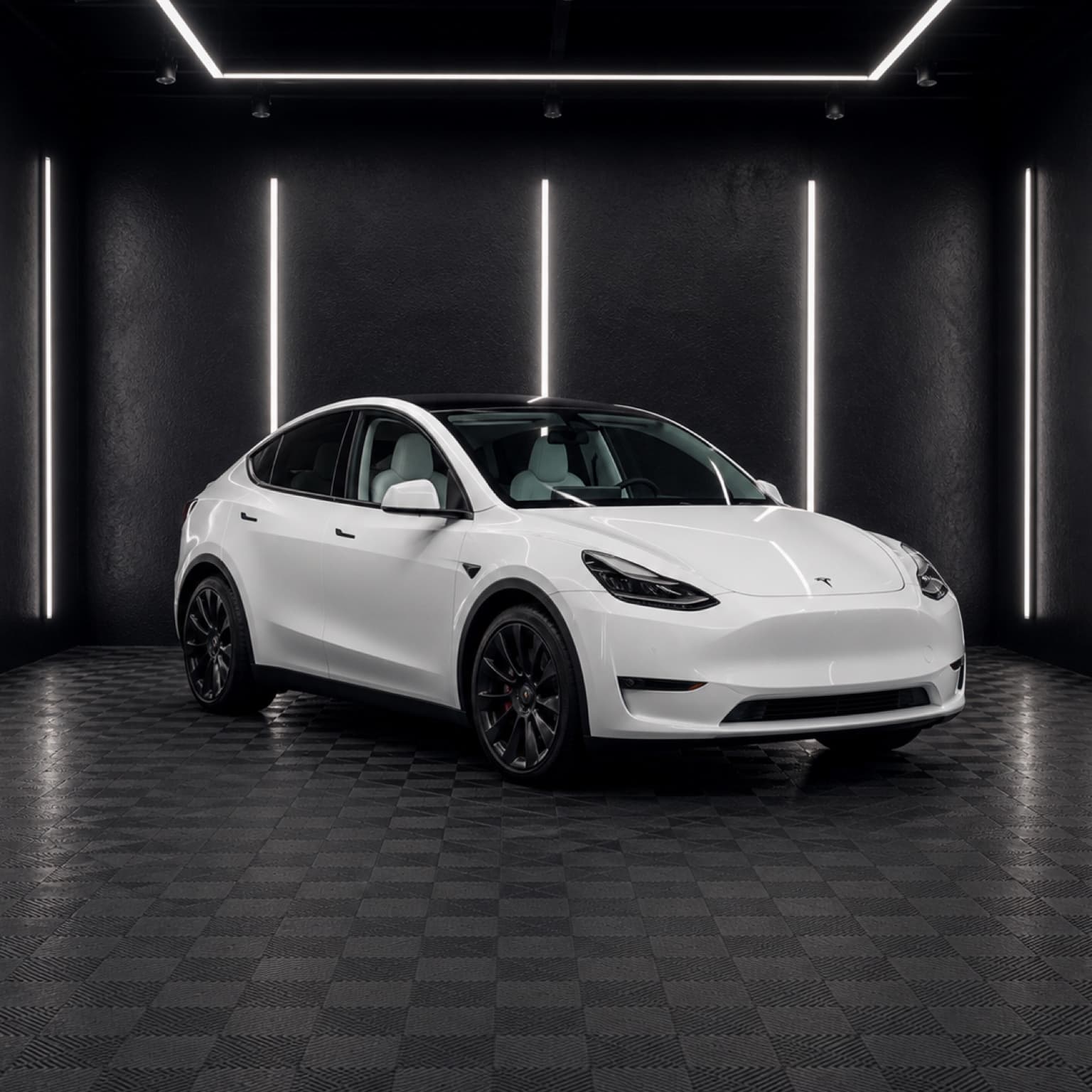 White Tesla Model Y inside a dark automotive studio.