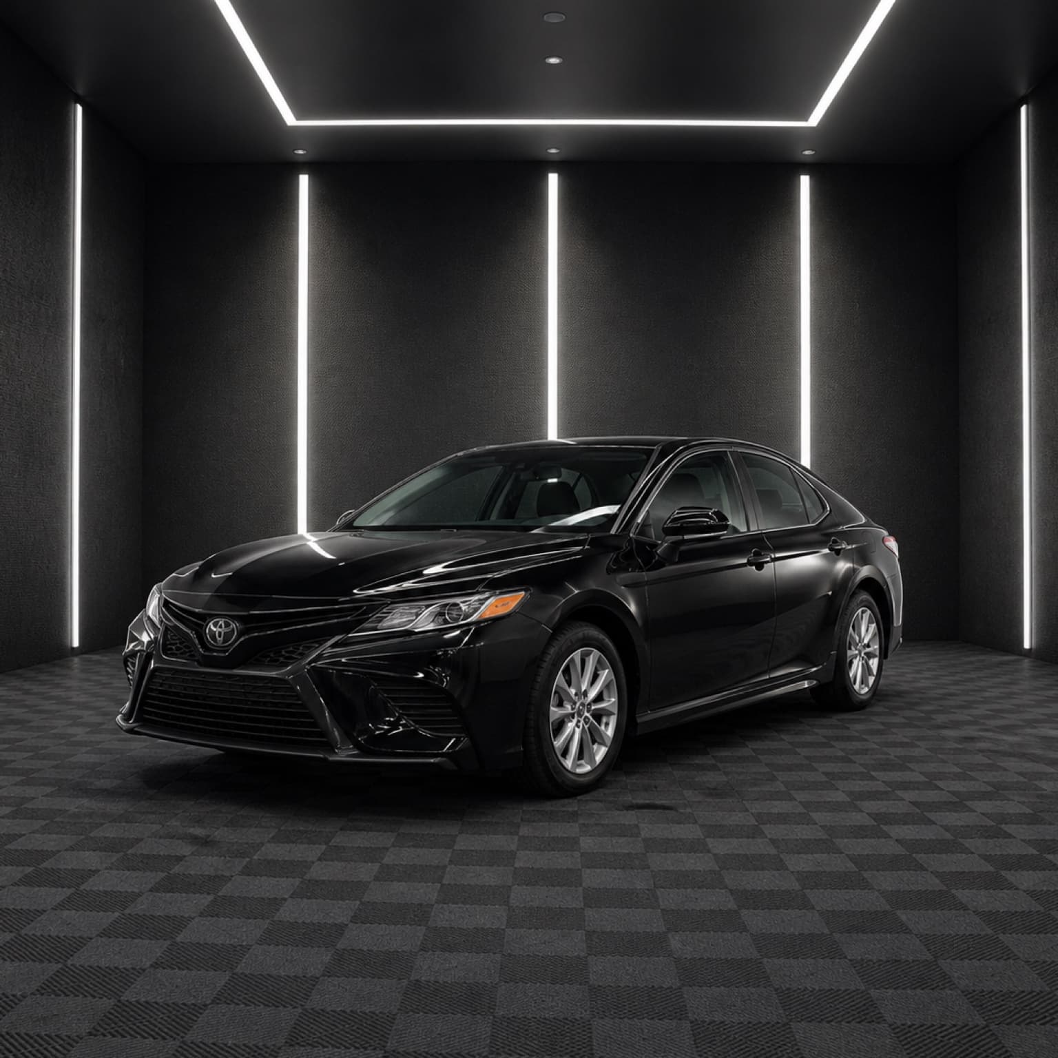 Black Toyota Camry inside a dark automotive studio.